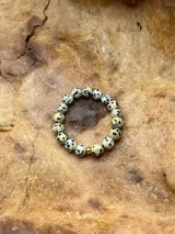 Anillo elástico de cuentas redondas de piedra dálmata con una cuenta dorada.