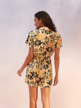 Mono corto negro con cuello camisero, cierre frontal con botones y lazo en la cintura.