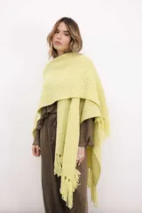 Ruana tejida en lana merino color amarillo pastel, con terminación de flecos.
