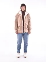 Campera color beige con interior de piel sintética blanca, capucha, cierre frontal con botones a presión, bolsillos laterales con solapa y puños elásticos.