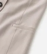 Chaleco color beige con escote halter, corte al cuerpo y cierre frontal con botones. Presenta un bolsillo de ojal en el frente.