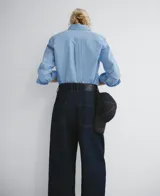 Pantalón de denim azul oscuro, corte barrel fit, con triple pespunte a contraste en interior y exterior de la pierna, cierre con botón metálico, trabillas y cinco bolsillos.