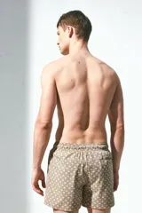 Short de baño color marrón con estampado de palmeras, con cintura elástica ajustable con cordón, bolsillos laterales y trasero con cierre autoadherente.