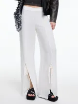 Pantalón ancho color blanco, de lino y viscosa, con tajos y lazos en la botamanga.