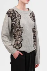 Sweater gris de cashmere y lana con estampado floral en negro y beige en los hombros.