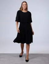 Vestido midi negro con corte a la rodilla, de seda fría, con capa superior superpuesta y mangas cortas.