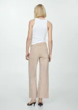 Pantalón culotte color beige de tejido tejano vaquero elástico, con tiro alto, trabillas, bolsillos delanteros y traseros, cierre de cremallera y botón, y bajo deshilachado.
