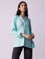 Camisa celeste texturada con cuello con solapa y abertura central con botones. Delantera con bolsillo aplicado y largo de manga regulable con presilla y botón.