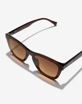 Lentes de sol Hawkers modelo Downtown Max, unisex, con montura cuadrada color marrón y lentes degradadas en tonos marrón y amarillo.