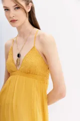 Vestido largo color mostaza, con breteles finos cruzados en la espalda y detalles de canutillos bordados.