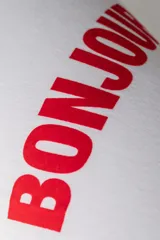 Remera blanca de corte boxy con estampa roja de la palabra "Bonjour" en el frente.