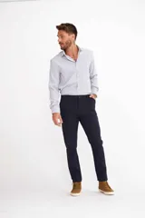 Pantalón de vestir color beige, de corte recto, con bolsillos laterales y traseros. Se ajusta a la cintura con cinturón de cuero marrón.