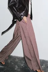 Pantalón de tiro medio con cintura elástica y bolsillos laterales ocultos en costura. Pierna ancha y estampado a rayas verticales color borgoña y blanco.