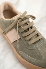 Zapatilla deportiva de cuero color verde oliva con detalles en rosa y suela marrón.