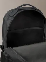 Mochila negra de poliéster reciclado con diseño minimalista. Presenta doble compartimento principal con cremallera, doble bolsillo exterior frontal con cremallera y parche con el logo de Calvin Klein.