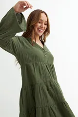 Vestido corto color azul marino, de manga larga con volado en el puño y corte en capas con volados en el cuerpo. Presenta cuello en V con botones frontales.