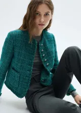 Chaqueta de tweed color verde azulado con cuello redondo, cierre frontal con botones efecto joya, dos bolsillos de parche delanteros, terminaciones deshilachadas y forro interior.