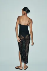 Vestido midi semitransparente de encaje negro, con escote recto, tirantes finos ajustables, forro interior tipo body con aros y abertura lateral en el bajo.