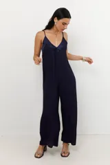 Mono de mujer color azul marino, con escote en V profundo y tirantes finos. Presenta un detalle de tela satinada en el escote.