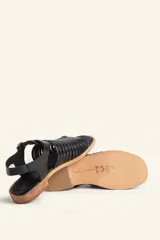 Sandalia de cuero color marrón con diseño de tiras entretejidas y hebilla lateral.