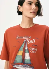 Remera color ladrillo con estampa de un velero y texto "Sunshine Sail Yatch Club".