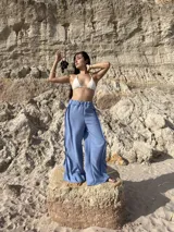 Pantalón ancho de tiro alto, color celeste claro, con costuras visibles en contraste que recorren verticalmente las piernas.