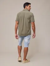 Camisa de algodón blanca de manga corta, con cuello abotonado y botones frontales.