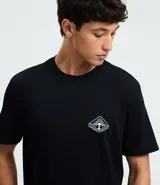 Remera masculina de manga corta, color negro, con cuello redondo. Presenta un estampado pequeño en el pecho con un diseño geométrico y un estampado grande en la espalda con un paisaje natural y la frase "Inspired & Discover".