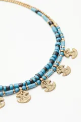 Collar doble con cuentas azules y negras, y dijes dorados con forma de ancla.