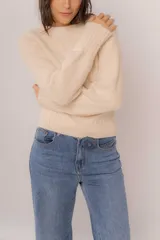 Buzo clásico de punto color beige con diseño de tejido suave, de corte ajustado y mangas largas.