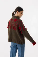 Sweater tejido de punto color crudo con cuello alto y diseño de rombos marrones con flecos.