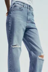 Pantalón de jean celeste de tiro alto, corte mom fit, largo regular y roturas en las rodillas.