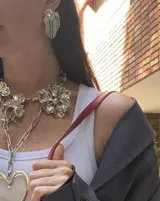Par de aros colgantes con forma de corazón de cristal y flecos de strass plateados.