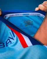 Camiseta de fútbol Umbro del Club Nacional de Football, modelo Alternativa 3. Diseño celeste con detalles en blanco y rojo en cuello y mangas. Incluye logo de Umbro, escudo del club y sponsor Antel en el frente.