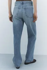 Pantalón de jean celeste de tiro alto, corte recto y largo hasta el tobillo. Tiene cinco bolsillos, trabillas en la cintura, efecto lavado y cierre frontal con cremallera y botón.