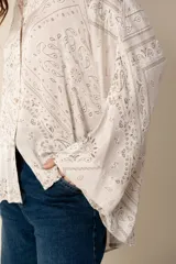 Camisa blanca con estampado de diseño bandana en tonos beige, de corte amplio, con cuello camisero y cierre frontal con botones.
