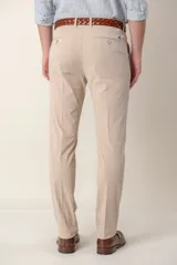 Pantalón de vestir color gris claro, de corte slim fit, con bolsillos laterales y traseros. Se ajusta a la cintura con cinturón de cuero marrón.