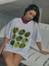 Remera oversized blanca con estampado gráfico de aceitunas verdes y rojas, de manga corta.