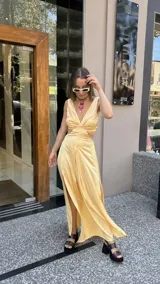 Vestido largo color durazno con escote pronunciado en V y aberturas laterales en la cintura. Presenta un drapeado frontal y falda con tajo lateral.