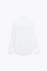 Camisa blanca de lyocell con cuello solapa, manga larga y bajo asimétrico. Cierre frontal con botones.