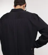 Camisa negra de poliéster con cuello inglés, manga larga, abotonada adelante y textura con rayas verticales.