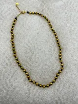 Collar corto de perlas doradas con hilo de seda azul marino y cierre de mosquetón dorado con cadena de extensión.