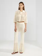 Camisa corta de punto abierto color negro, con cuello polo, mangas 3/4 y cierre frontal con botones.