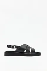 Sandalias negras de símil cuero con agarre ajustable en el talón y capellada entrelazada. Plataforma de 3 cm de alto.