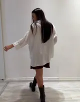 Camisa oversize rosada de lino, con cuello clásico, cierre frontal con botones, dos bolsillos de parche en el pecho y mangas largas con puños abotonados.