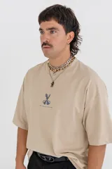 Remera color beige con estampado de una pieza de ajedrez en color naranja en la espalda.