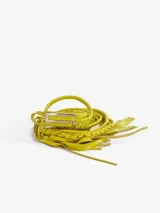 Cinturón amarillo de cuero trenzado con hebilla metálica plateada en forma de "S" y terminación con flecos.