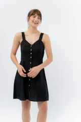 Vestido corto negro con breteles anchos, escote en V y abotonadura frontal.