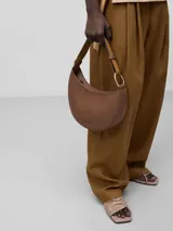 Bolso de hombro tipo baguette color crema, con textura granulada y asa corta regulable.