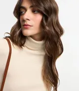 Suéter de punto color blanco, con cuello alto estructurado, manga larga y efecto texturizado.